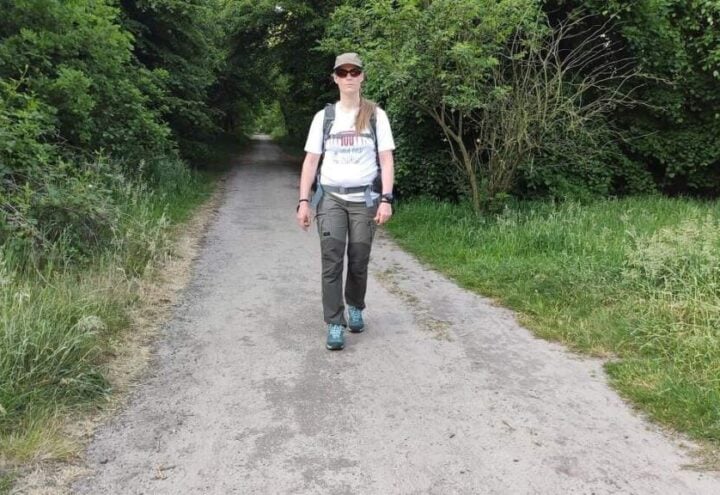Wandelaar loopt over een onverhard pad tussen dicht groen